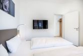 Schlafzimmer mit Doppelbett und TV