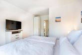 Schlafzimmer "1" mit Boxspringbett, TV und Blick zum Flur