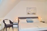 Schlafzimmer mit Doppelbett und Sessel