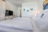 Schlafzimmer mit Doppelbett, Kleiderschrank und TV