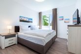 Schlafzimmer mit Doppelbett, Kommode und TV